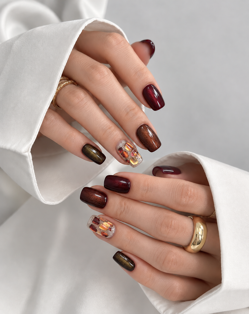 Close-up of autumn jewel-tone manicure with glossy press-on nails