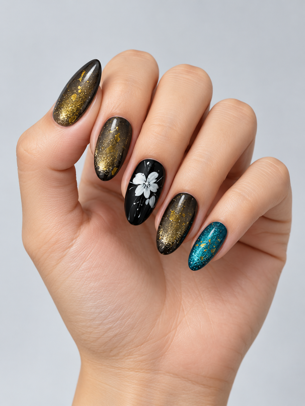 Close-up of dark shimmer press-on nails with white flowers, gold foil accents and teal metallic detail