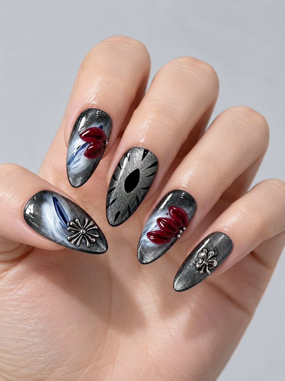 Close-up of silver metallic press-on nails with red sculpted petals, marbled accents and decorative charms