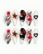 Handmade long almond press-on nails with sculpted red roses, oversized crystals, pearls, silver details and black heart accents