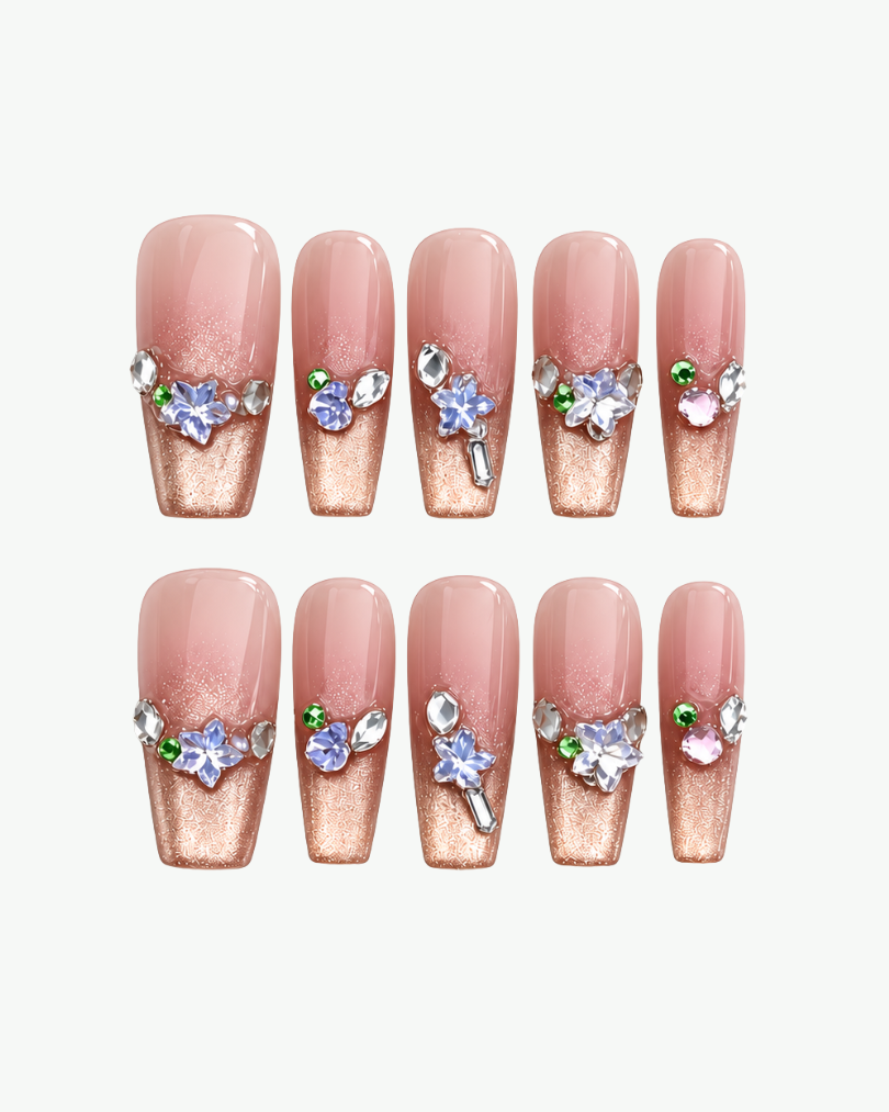 Close-up of champagne gold coffin press-on nails with floral details and sparkling crystal accents