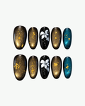 Handmade smoky brown and black almond press-on nails with white floral art, gold shimmer and teal metallic accents