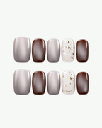 Handmade neutral short squoval press-on nails in smoky grey, mocha brown and white with gold foil accents