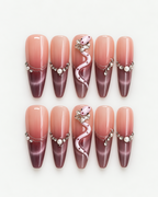 Extra long stiletto press-on nails with blush-to-plum ombre, pink snake detail, pearls and crystal accents