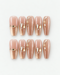 Champagne shimmer long coffin press-on nails with glossy nude sections and sculptural gold jewellery accents